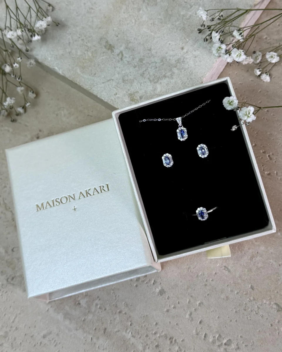 Nuestra esencia: caja Maison Akari abierta con el set Tanzanita y flores blancas — Maison Akari